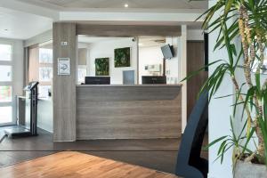 un hall de bureau avec une réception et des plantes dans l'établissement Zenitude Hôtel Résidences Roissy Village, à Roissy-en-France