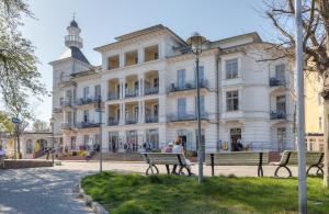 Eine Frau, die vor einem Gebäude auf einer Bank sitzt. in der Unterkunft Villa Seeschloss in Heringsdorf