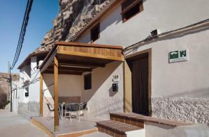 un edificio con portico attrezzato con tavolo e sedie di Casa Cueva "EL PORCHE DEL JUCAR" ad Alcalá del Júcar