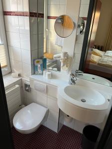 ein Badezimmer mit einem weißen WC und einem Waschbecken in der Unterkunft Gästehaus Janßen in Cuxhaven