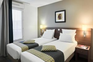 a hotel room with two beds and a window at Zenitude Hôtel Résidences Roissy Village in Roissy-en-France +15 photos