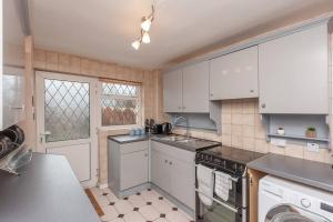 a kitchen with white cabinets and a stove top oven at Leed City Centre - Armley Wortley in Leeds