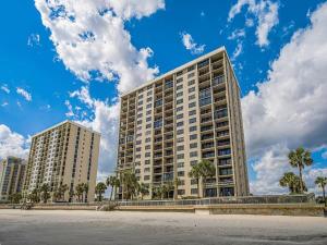 a large building with palm trees in front of it at Arcadian Getaway - Oceanfront Condo, With Pool and Wifi, Monthly Winter Rental in Myrtle Beach