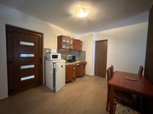 a kitchen with a table and a white refrigerator at Családi Villa in Balatonszemes