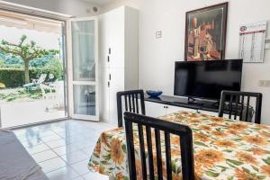 uma sala de jantar com televisão, mesa e cadeiras em M355 - Marcelli, bilocale con giardino e parcheggio em Marcelli