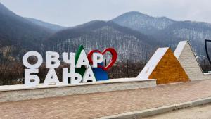 una señal que lee Sasha olímpica con montañas en el fondo en Dom Plus, en Ovčar Banja