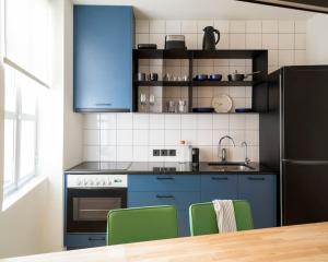 a kitchen with blue cabinets and green chairs at Hoppersgr- Amazing apt in the heart of Athens - 5 in Athens