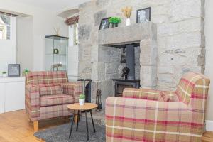 a living room with two chairs and a stone fireplace at The Gate House - 3 Bed & Parking in Edinburgh