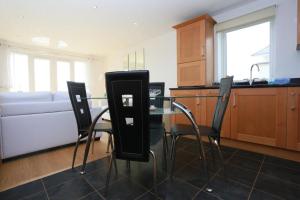 uma cozinha com uma mesa de vidro com cadeiras e um sofá em Bournecoast: Two bedroom flat with stunning panoramic views - FM2775 em Bournemouth