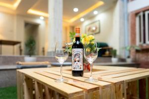 una bottiglia di vino e due bicchieri su un tavolo di legno di Nyadha House Bed & Breakfast a Patan