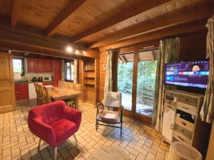 un salon avec une chaise rouge et une télévision dans l'établissement LE MONTAGNARD Chalet en bois, à La Bresse
