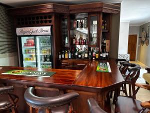 un bar con una gran mesa de madera y sillas en Meyers Guesthouse, en Jwaneng