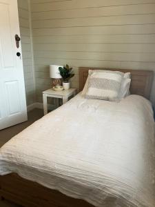 a bed with a white comforter and a side table at Antique Retreat in Bathurst