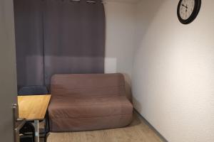 a room with a couch and a clock on a wall at Au cœur des Cîmes en Chartreuse in Saint-Pierre-de-Chartreuse