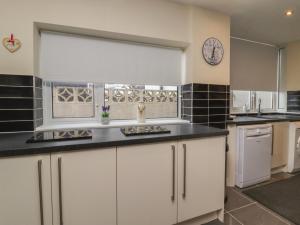 a kitchen with white cabinets and black counter tops at 19 Slinger Road in Cleveleys
