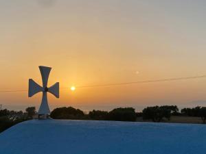 une croix sur le toit avec le coucher de soleil en arrière-plan dans l'établissement Summer View, à Theologos