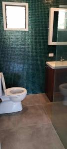 a bathroom with a toilet and a green tiled wall at Dream Cove Cottage, 2 Bedroom in Port Vila