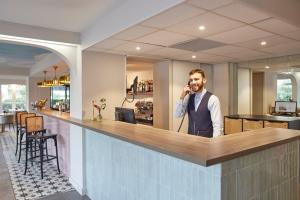 un hombre hablando por celular en un bar en Hotel-Restaurant Isidore Nice Ouest, en Niza