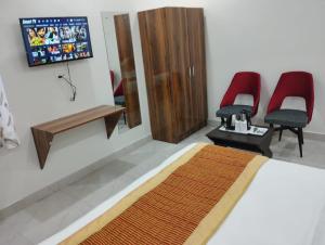 a bedroom with a bed and two red chairs at Hotel Fortune Residency in New Delhi