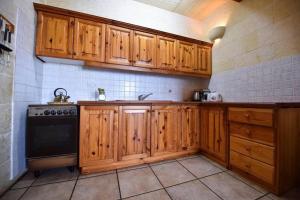 - une cuisine avec des placards en bois et une cuisinière dans l'établissement Tal-Bahar Farmhouse, Zebbug Gozo, à Żebbuġ