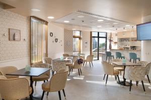 a dining room with tables and chairs and a tv at DOMITYS LE PARC DES AUBIERS in Poissy