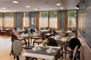 a restaurant with tables and chairs and windows at DOMITYS LE PARC DES AUBIERS in Poissy