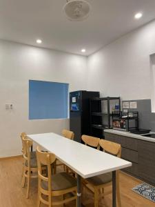 a white table and chairs in a kitchen with a blue screen at Alphabet Home Capsule in Ho Chi Minh City