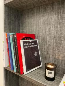 a shelf with books and a candle next to a candle at Alphabet Home Capsule in Ho Chi Minh City