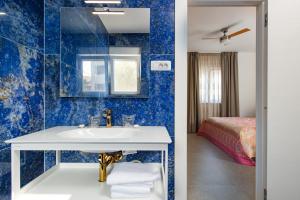 ein Bad mit blauen Wänden, einem Waschbecken und einem Bett in der Unterkunft Luxury apartments Brijuni in Valbandon