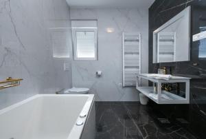 ein weißes Bad mit einer Badewanne und einem WC in der Unterkunft Luxury apartments Brijuni in Valbandon