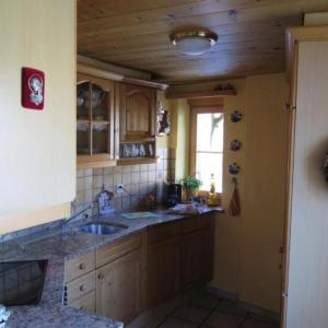cocina con armarios de madera, fregadero y ventana en Haus 116A en Tarasp