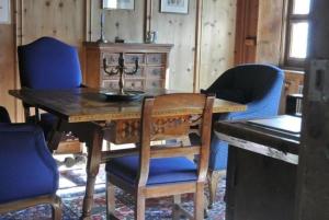 comedor con mesa de madera y sillas azules en Chesa Perini-Albertini en La Punt-Chamues-ch
