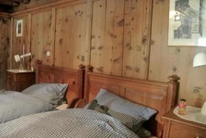 1 dormitorio con 1 cama y pared de madera en Chesa Perini-Albertini en La Punt-Chamues-ch