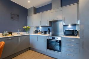 a kitchen with white cabinets and a stove top oven at Elliot Oliver - Loft Style 2 Bedroom Apartment With Parking In The Docks in Gloucester