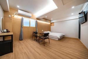 um quarto com uma cama, uma secretária e uma mesa em Lime Hotel em Busan