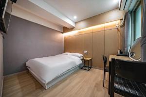 a bedroom with a large white bed and a table at Lime Hotel in Busan