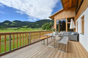 eine Holzterrasse mit einem Tisch und Stühlen darauf in der Unterkunft Voglen 2 in Nesselwang