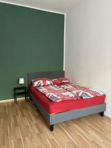 ケルンにあるUnterkunft in Köln - Nähe Messe und Flughafenの緑の壁のベッドルーム1室(赤いシーツ付きのベッド1台付)