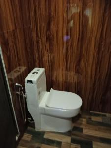 a white toilet in a bathroom with wooden walls at Lakenest overnight in Alleppey