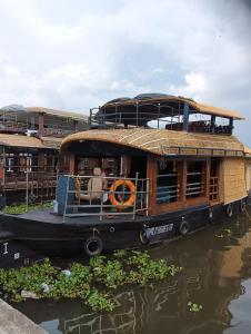 a boat sitting in the water next to a building at Lakenest overnight in Alleppey