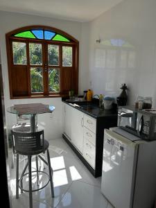 a kitchen with a counter and a table and a refrigerator at Pousada Casa do Jova em Raposo RJ 