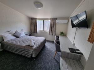 um quarto de hotel com uma cama e uma televisão de ecrã plano em Y Motels Yarraman em Yarraman