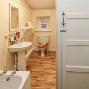 La salle de bains est pourvue d'un lavabo, de toilettes et d'une porte. dans l'établissement Beautiful Countryside Cottage Alnwick, à Alnwick