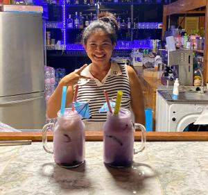 Jing Jo Boutique Bungalow في سام رويْ يوت: امرأة تجلس في مكتب مع اثنين من الحليب المخفوق