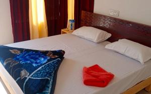 uma cama com duas almofadas e uma toalha vermelha em Hotel Village Inn by StayApart em Barkot