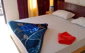 a bed with a blanket and a red towel on it at Hotel Village Inn by StayApart in Barkot
