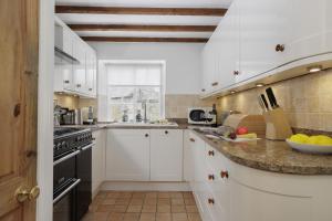 een keuken met witte kasten en een aanrecht bij The Carriage House in Blockley