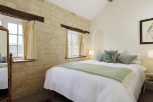 a bedroom with a large bed in a room with windows at The Carriage House in Blockley