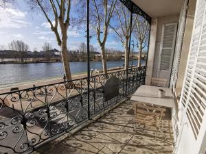 Un balcón con una mesa y vista al agua. en Appart Gîte Les Oiseaux- face Loire Quai du Châtelet, en Orléans