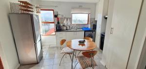 a kitchen with a table and chairs and a refrigerator at Laguna Beach K60 - Greenways Golf Estate on Sea in Cape Town